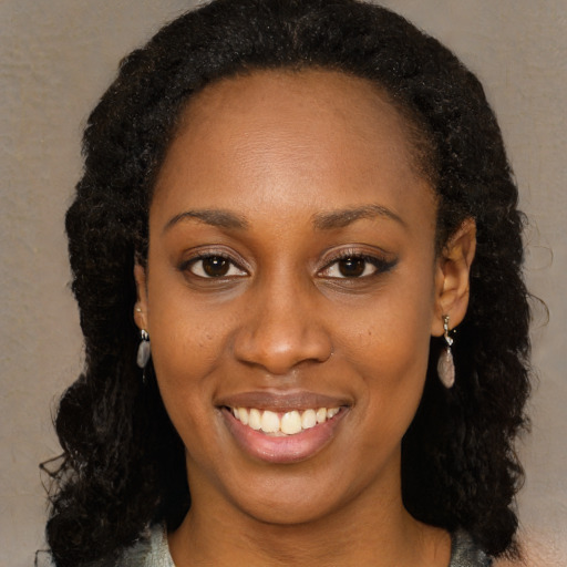 Joyful black young-adult female with long  black hair and brown eyes