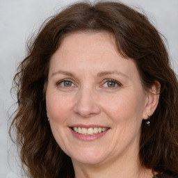 Joyful white adult female with medium  brown hair and green eyes