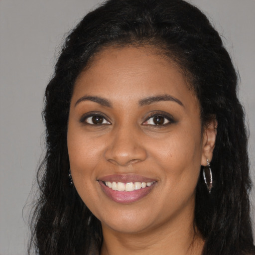 Joyful black young-adult female with long  black hair and brown eyes