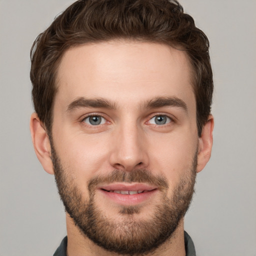 Joyful white young-adult male with short  brown hair and grey eyes