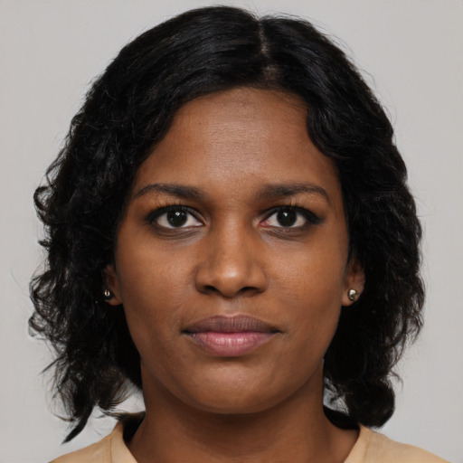Joyful black young-adult female with long  brown hair and brown eyes