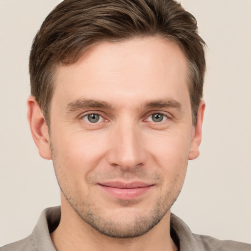 Joyful white young-adult male with short  brown hair and grey eyes