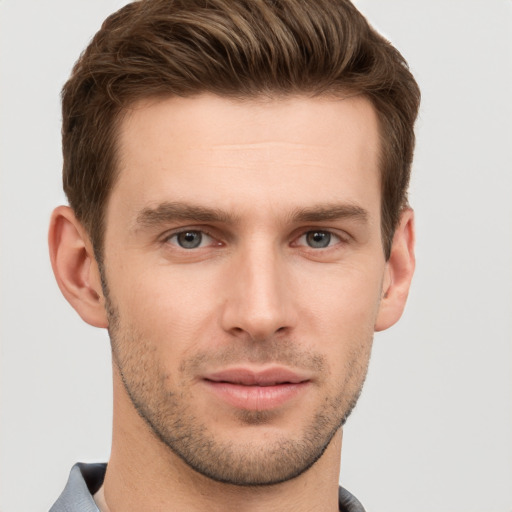 Joyful white young-adult male with short  brown hair and grey eyes