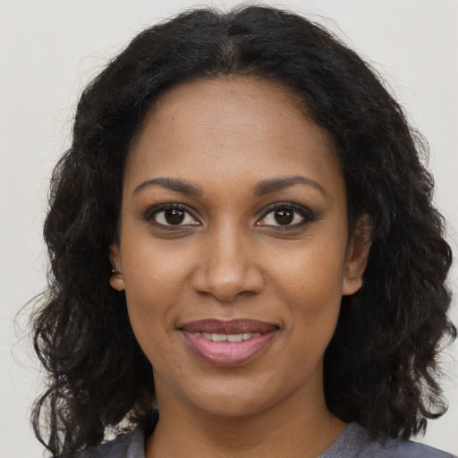 Joyful black young-adult female with long  brown hair and brown eyes