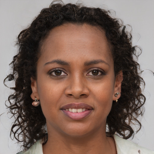 Joyful black young-adult female with long  brown hair and brown eyes