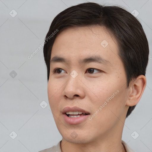 Joyful asian young-adult male with short  brown hair and brown eyes