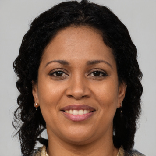 Joyful black young-adult female with long  brown hair and brown eyes