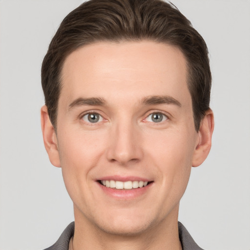 Joyful white young-adult male with short  brown hair and grey eyes