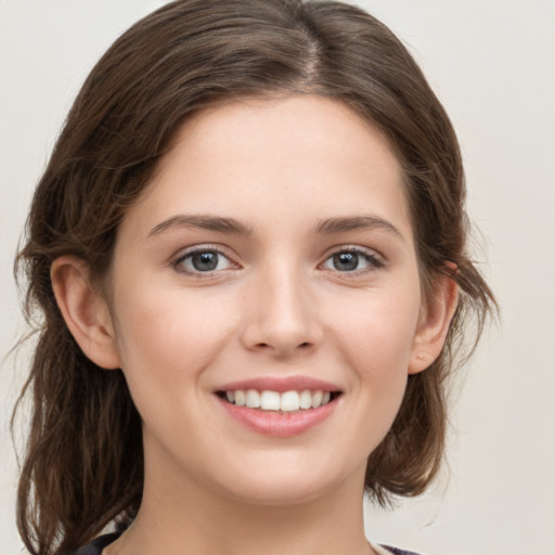 Joyful white young-adult female with medium  brown hair and green eyes