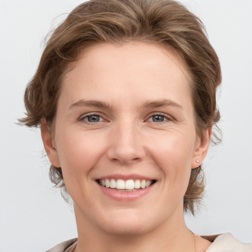 Joyful white young-adult female with medium  brown hair and grey eyes