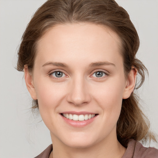 Joyful white young-adult female with medium  brown hair and grey eyes