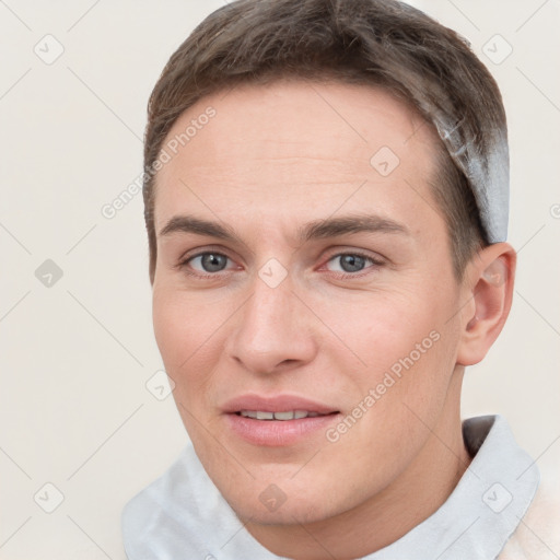 Joyful white young-adult male with short  brown hair and grey eyes