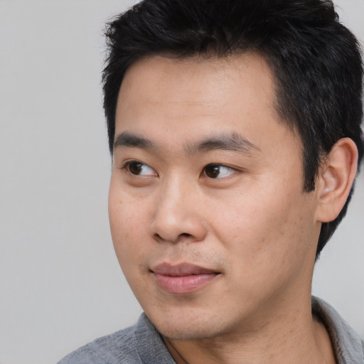 Joyful asian young-adult male with short  black hair and brown eyes
