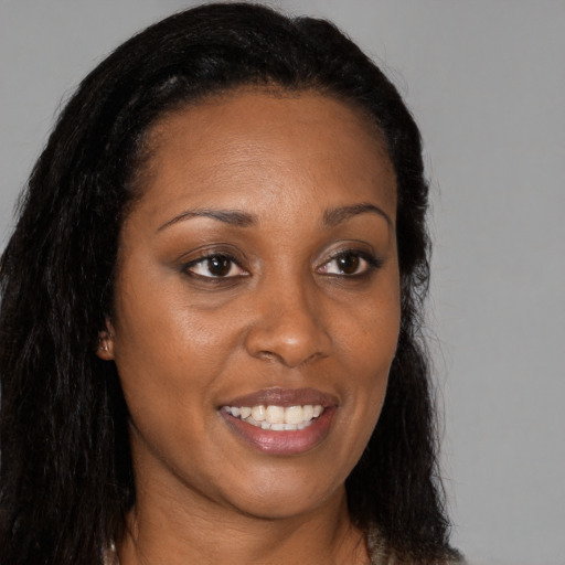 Joyful black young-adult female with long  brown hair and brown eyes