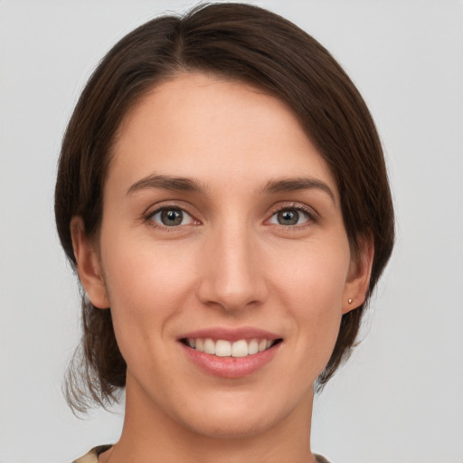 Joyful white young-adult female with medium  brown hair and green eyes