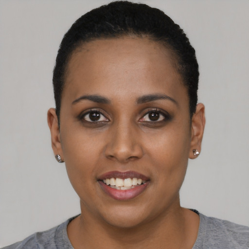 Joyful black young-adult female with short  black hair and brown eyes