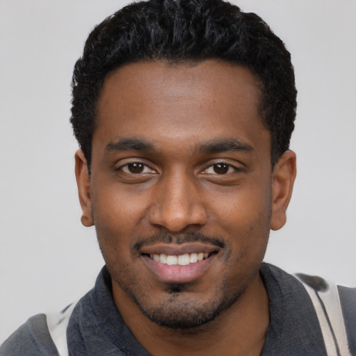 Joyful black young-adult male with short  black hair and brown eyes