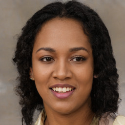 Joyful black young-adult female with long  brown hair and brown eyes