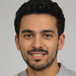 Joyful latino young-adult male with short  black hair and brown eyes