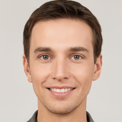 Joyful white young-adult male with short  brown hair and grey eyes