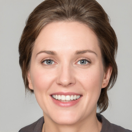 Joyful white young-adult female with medium  brown hair and grey eyes