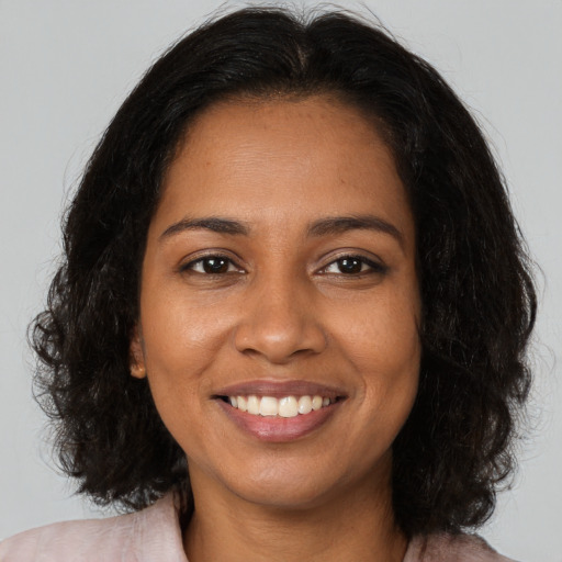 Joyful black young-adult female with long  brown hair and brown eyes