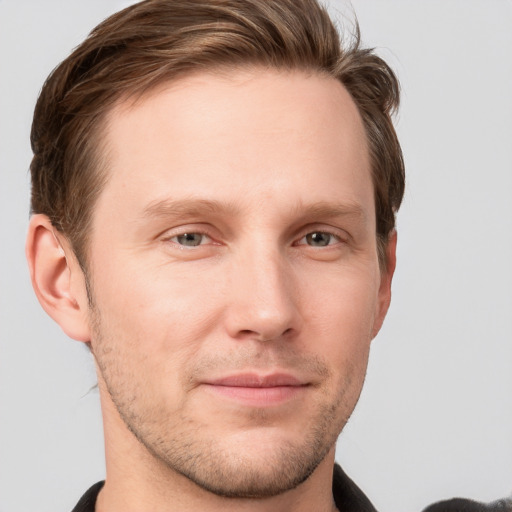 Joyful white young-adult male with short  brown hair and grey eyes