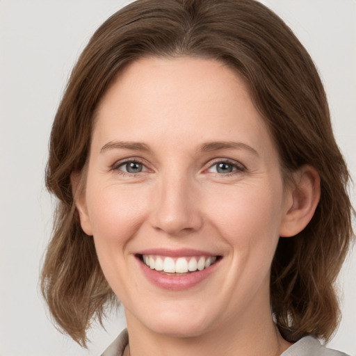 Joyful white young-adult female with medium  brown hair and grey eyes