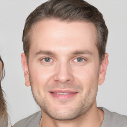 Joyful white young-adult male with short  brown hair and grey eyes