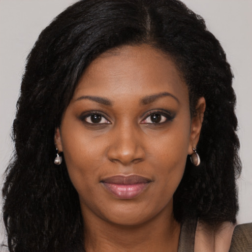 Joyful black young-adult female with long  black hair and brown eyes