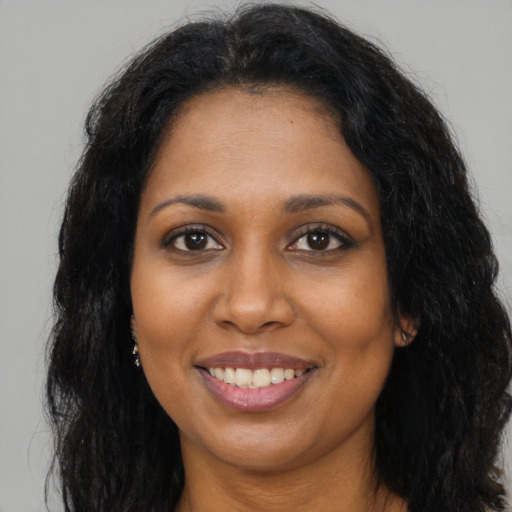 Joyful black young-adult female with long  brown hair and brown eyes