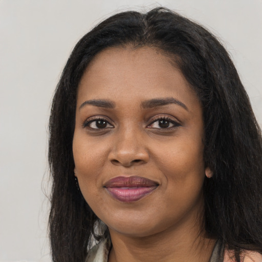 Joyful black adult female with long  brown hair and brown eyes