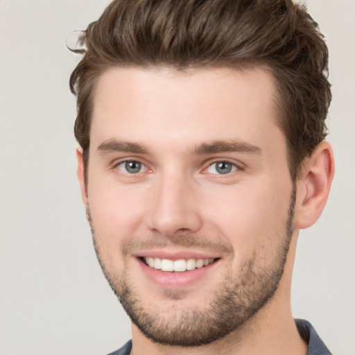 Joyful white young-adult male with short  brown hair and grey eyes