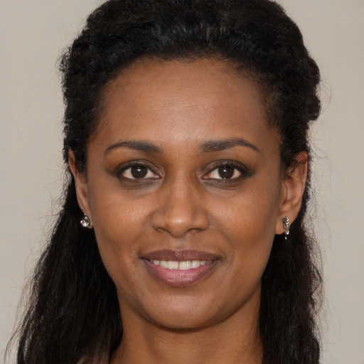 Joyful black young-adult female with long  brown hair and brown eyes