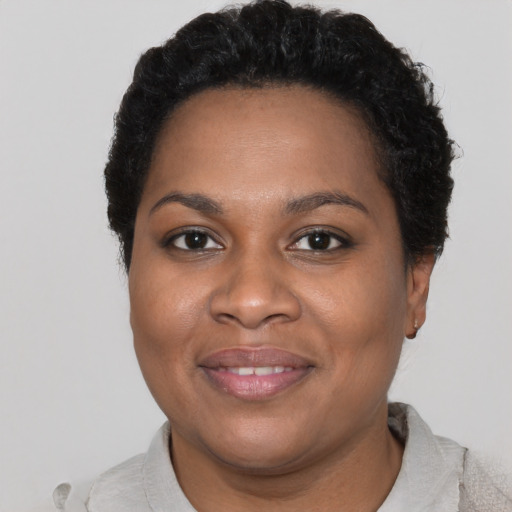 Joyful black young-adult female with short  black hair and brown eyes