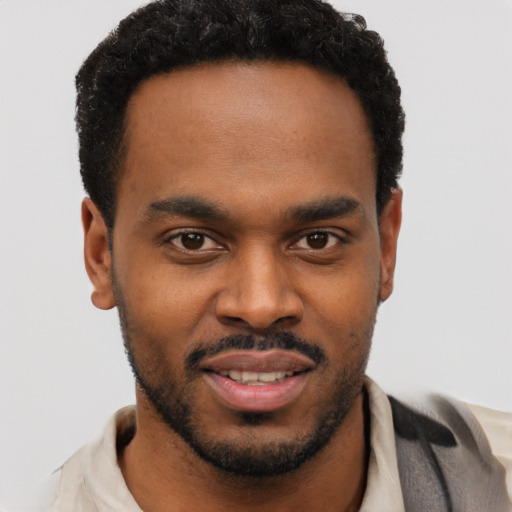 Joyful black young-adult male with short  black hair and brown eyes