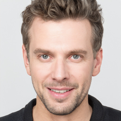 Joyful white young-adult male with short  brown hair and grey eyes