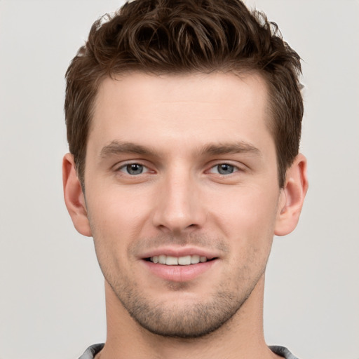 Joyful white young-adult male with short  brown hair and grey eyes