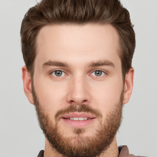 Joyful white young-adult male with short  brown hair and grey eyes