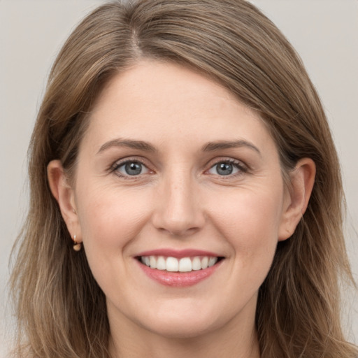 Joyful white young-adult female with long  brown hair and grey eyes