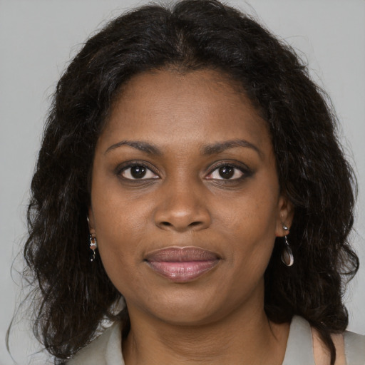 Joyful black adult female with long  brown hair and brown eyes