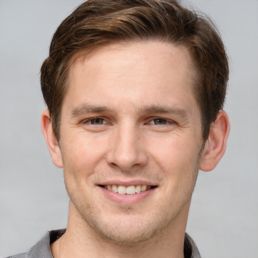 Joyful white young-adult male with short  brown hair and grey eyes