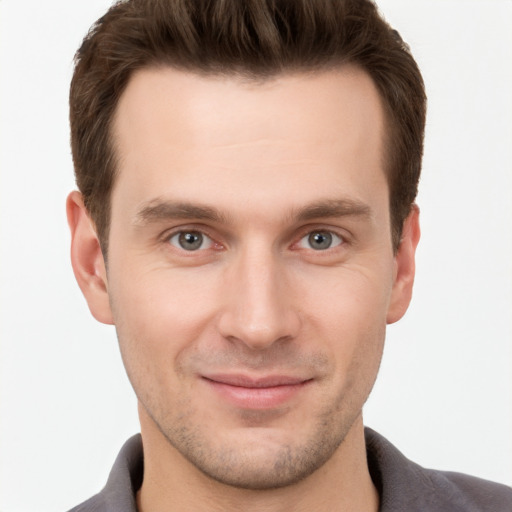 Joyful white young-adult male with short  brown hair and grey eyes