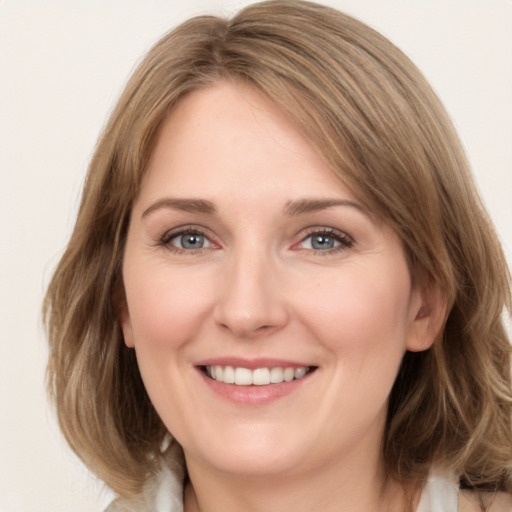 Joyful white young-adult female with medium  brown hair and green eyes