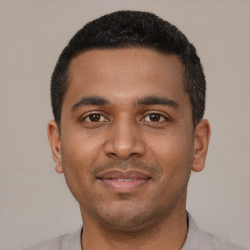 Joyful black young-adult male with short  black hair and brown eyes