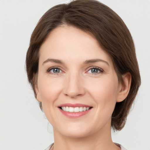 Joyful white young-adult female with medium  brown hair and grey eyes