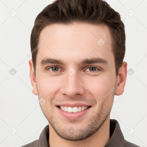 Joyful white young-adult male with short  brown hair and grey eyes