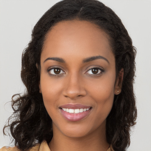 Joyful black young-adult female with long  brown hair and brown eyes