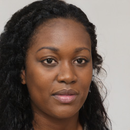 Joyful black young-adult female with long  brown hair and brown eyes