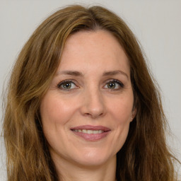 Joyful white adult female with long  brown hair and green eyes